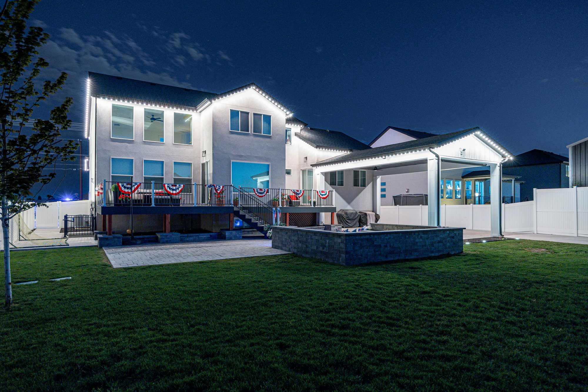 Same backyard by night — roofline illuminated
